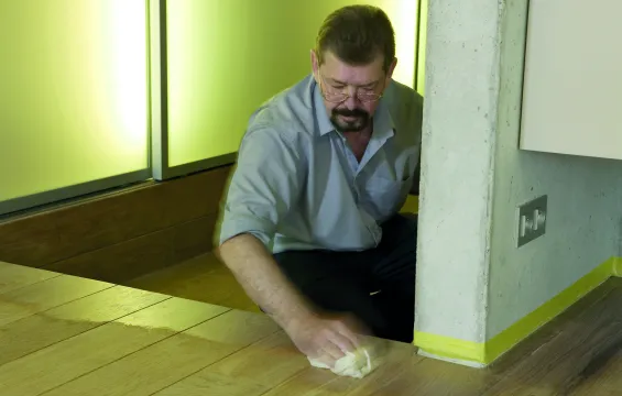 George Barrell is oiling a wooden floor and stairs