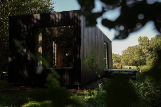A black cabin in the woods in a rustic environment