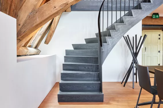 Black open staircase in a rustic room with wooden floors and beams