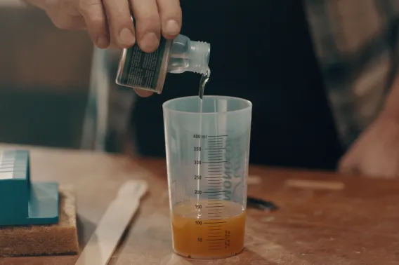 The B-component is being added to the oil in a mixing cup