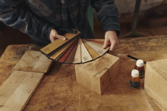 Someone is holding a wooden colour fan and choosing between a wide range of colours in a woodshop