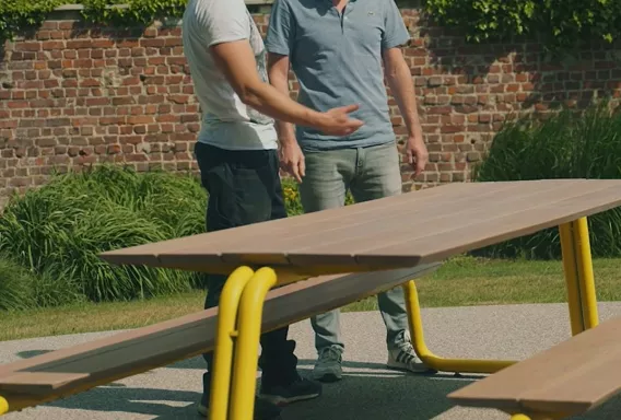 Two men are inspecting an outdoor table
