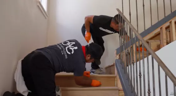 Two people are oiling a staircase
