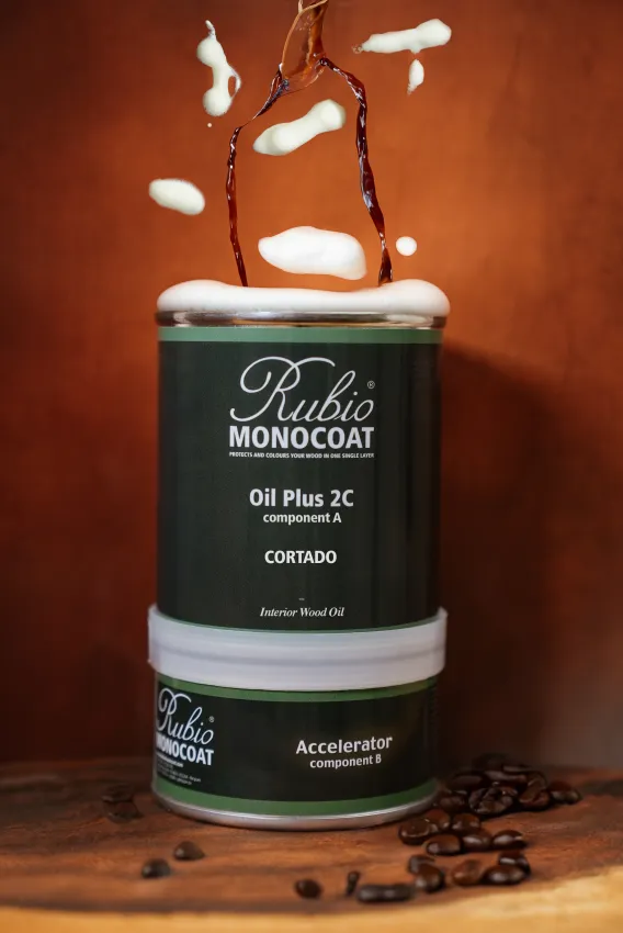 Creative and warm packshot of Oil Plus 2C in the colour Cortado with coffee and milk foam falling down on the can