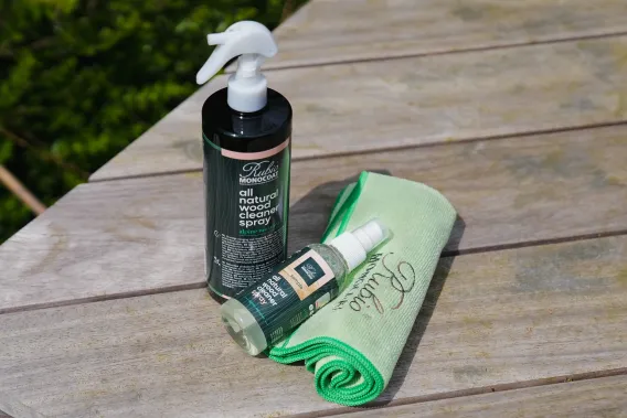 The All Natural Wood Cleaner and Spray are laying on a deck in the sun