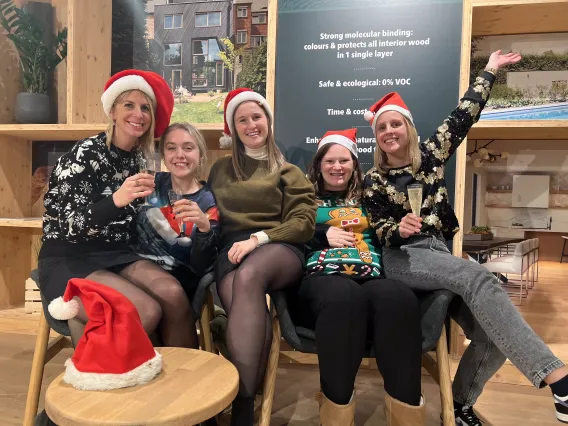 5 women are posing with Christmas hats in a showroom