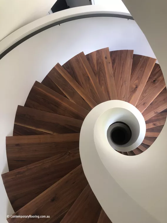 A round dark walnut staircase seen from above