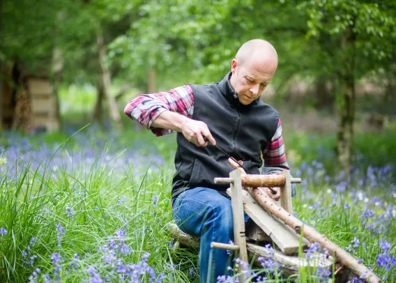 Nick is woodcarving in the middle of a forest. He's carving a trunk