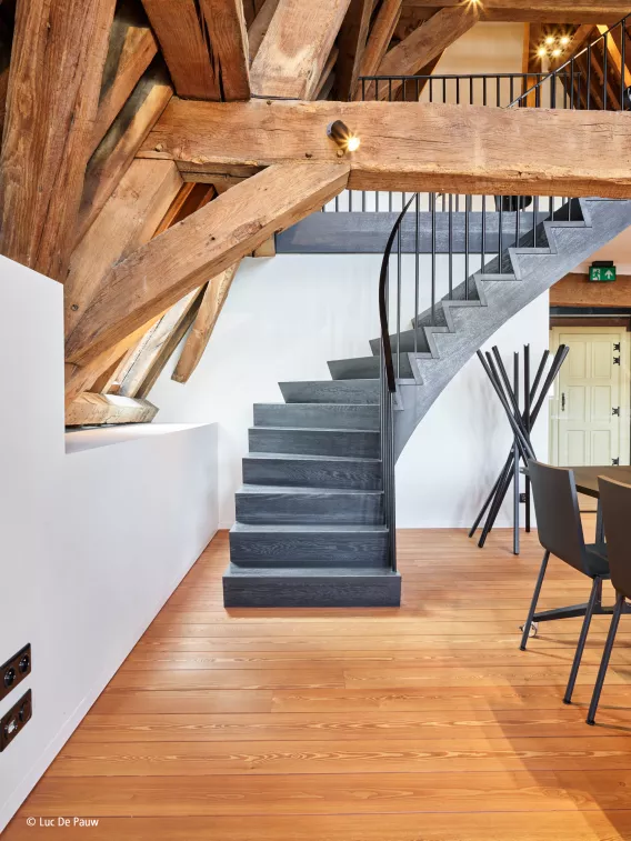 Black staircase in a meeting room with natural wooden beams and floors