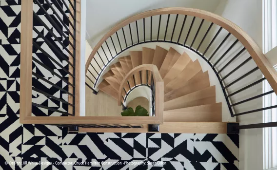 A half round stairs shown from above with a black and white rug