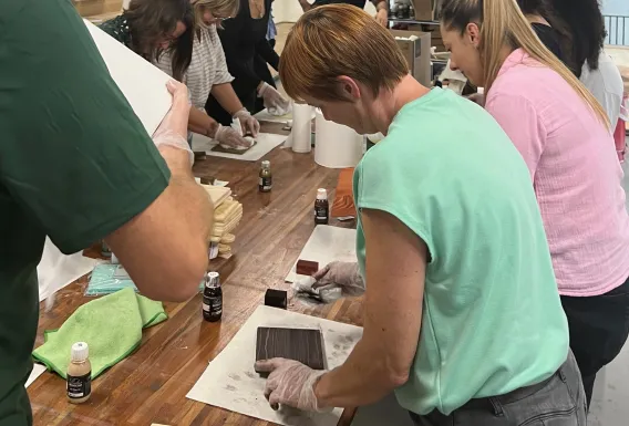 Employees are oiling a piece of wood on an internal training day