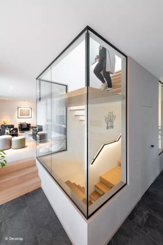 Floating staircase in a glass hallway with a person walking the stairs